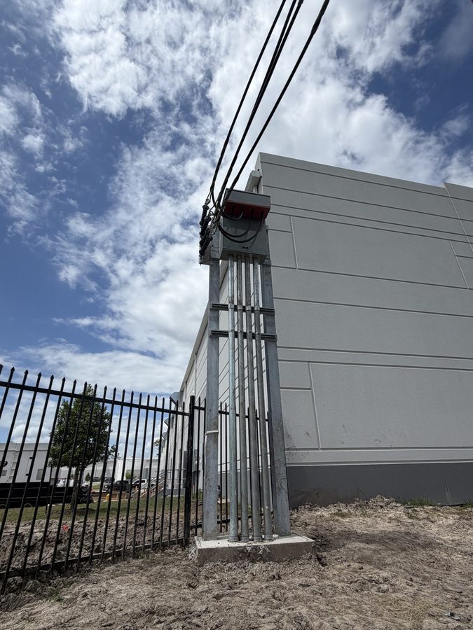 Low angle view of a galvanized service riser and meter cabinet against a building wall