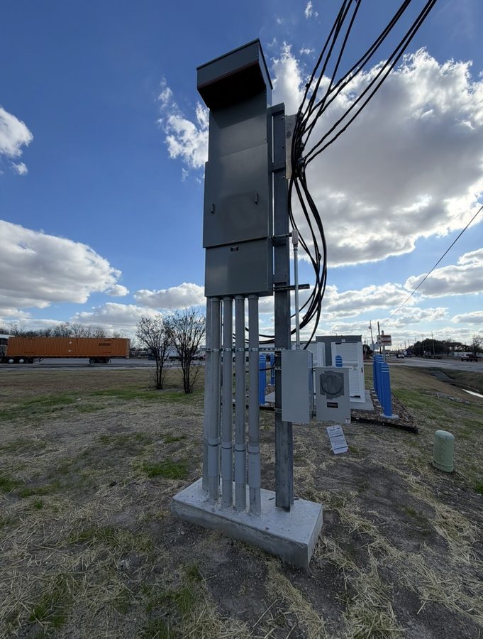 Tall new meter, panel and conduit assembly standing on its pad against a blue sky