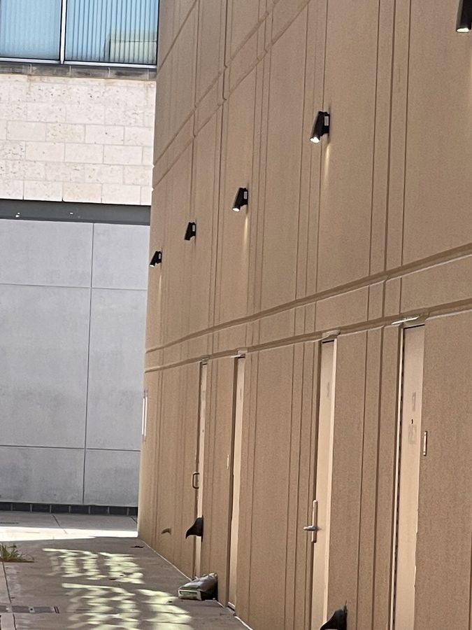 Row of bronze LED wall packs installed above the service doors of a commercial building