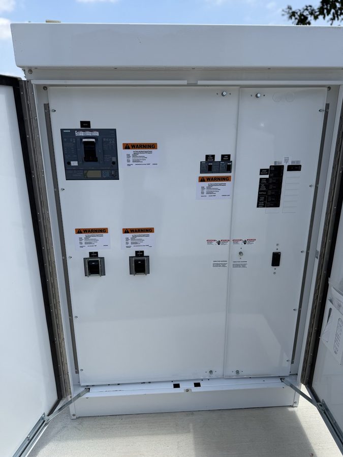 Open EV charger cabinet showing the breaker and the applied arc-flash warning labels