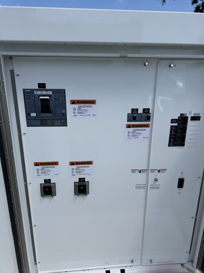 Exterior EV service enclosure with the main breaker and two 300-amp charger breakers landed