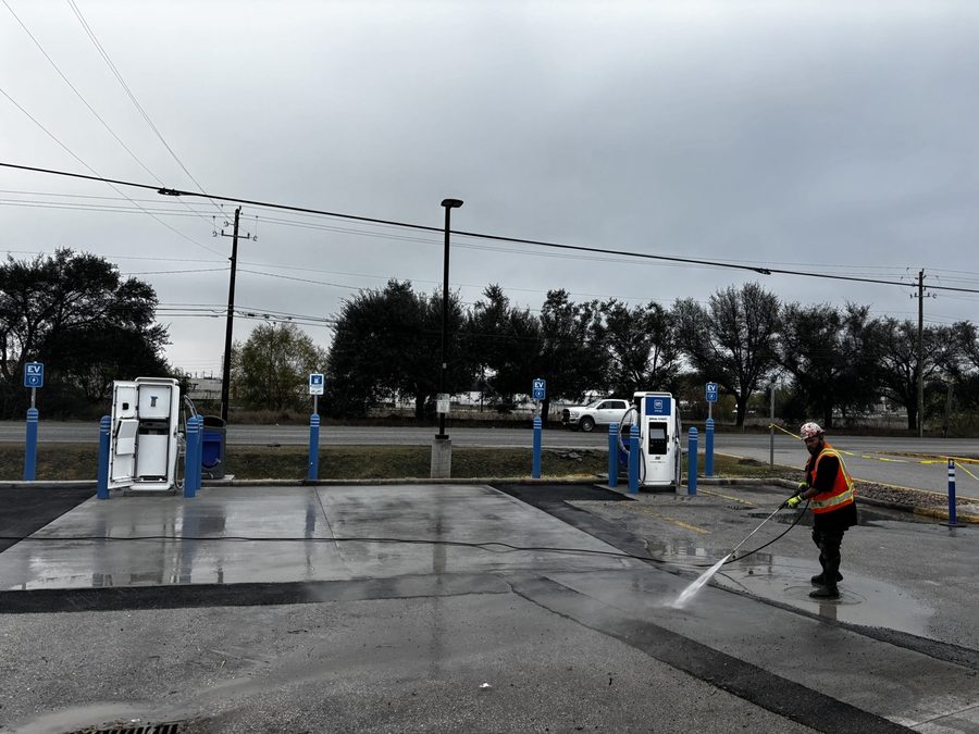 Crew member power-washing the pad at an EV charging site