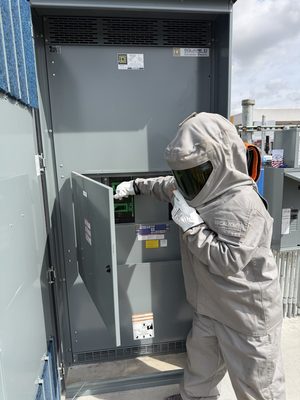 Technician in arc-flash PPE opening a safety disconnect