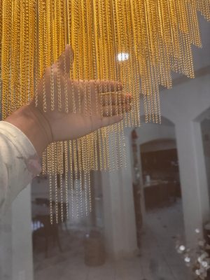 Hand adjusting the gold beaded strands on a newly hung chandelier