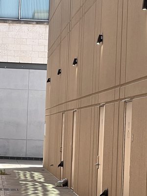 Row of bronze LED wall packs installed above the service doors of a commercial building