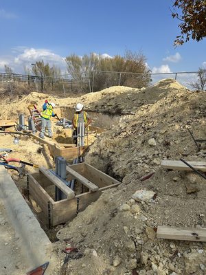 Two crew in hi-vis digging and building wood forms for an underground junction box