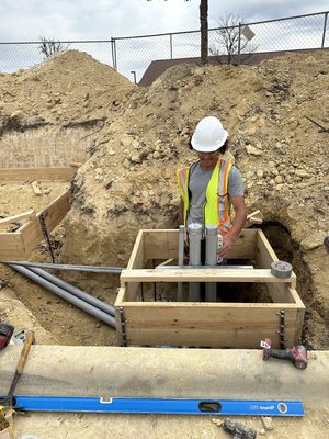 Crew member in a hard hat at a wood-formed conduit stub-up box