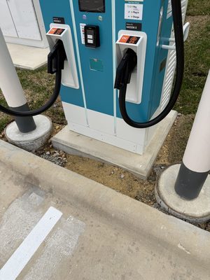 Close-up of a DC fast charger's dual connectors and payment touchscreen