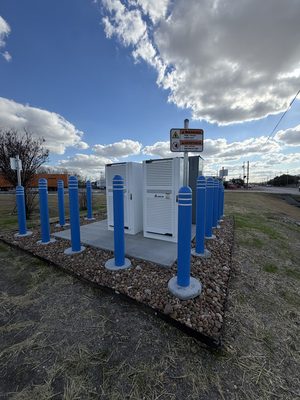 DC fast-charging power and inverter cabinets inside a ring of protective bollards