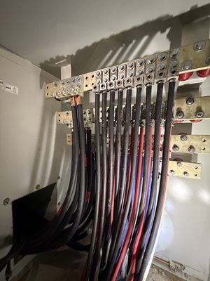Interior electrical room with heavy-gauge conductors landed on stacked bus-bar lugs