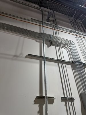 Neat EMT conduit runs with matched 90 degree bends along a warehouse wall and ceiling