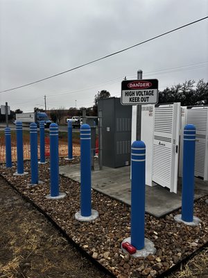 EV charging power cabinets behind bollards with danger high voltage signage in place