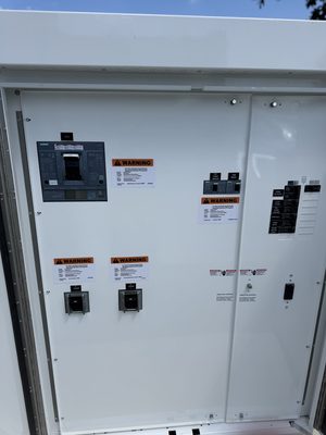 Exterior EV service enclosure with the main breaker and two 300-amp charger breakers landed