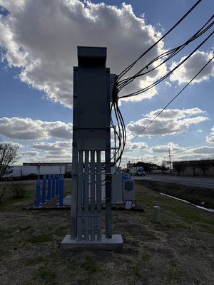 Conduit and meter pedestal for an EV charging site silhouetted against a dusk sky