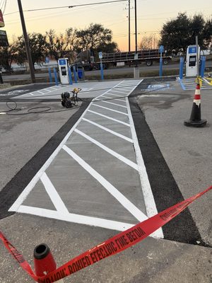 EV charging site at dusk with caution tape and a cone still up around the chargers