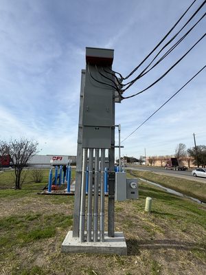 Exterior service riser and meter pole carrying multiple conduits against a blue sky