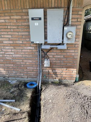 Automatic transfer switch, sub-panel and meter installed together as one assembly on a brick wall