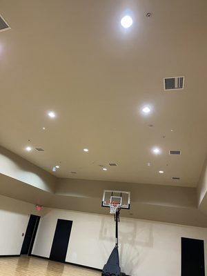 Gymnasium ceiling with new recessed cans above a basketball hoop