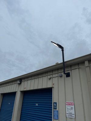 New LED area light on a pole bracket at a storage facility roofline, shot at dusk