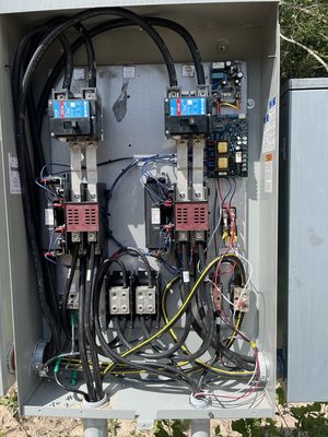 Open outdoor transfer switch cabinet showing the contactors and control board inside