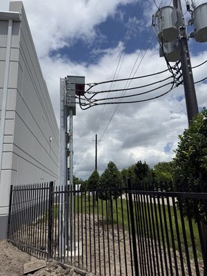 Riser with meter and CT cabinet, four service cables looping up to a pole transformer