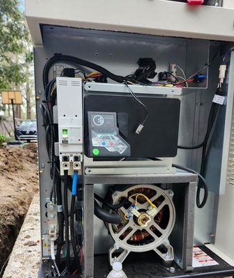 Home standby generator with its enclosure open during installation, showing the controller, the 150-amp main breaker and the alternator inside, with the supply trench still open alongside