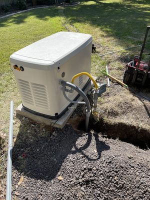 Standby generator set on a concrete pad with the gas hookup made up and the trench open alongside