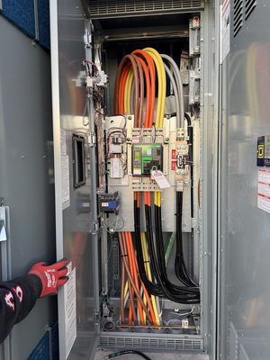 Technician opening large switchgear to a breaker with a digital display