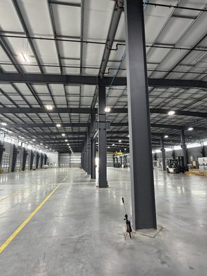 Warehouse interior after a high-bay LED retrofit, forklift and pallets below