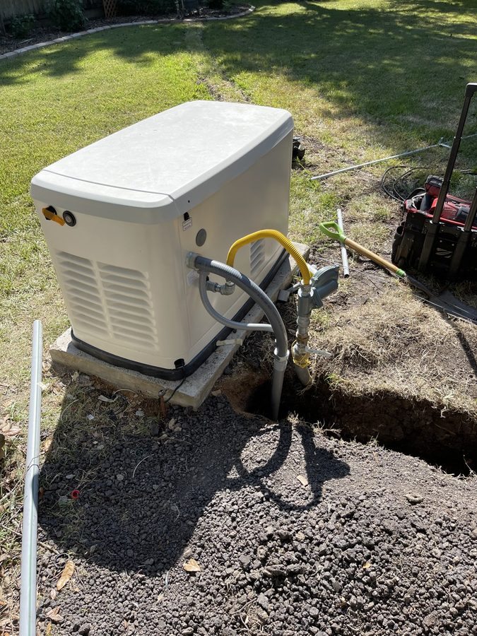 Standby generator set on a concrete pad with the gas hookup made up and the trench open alongside