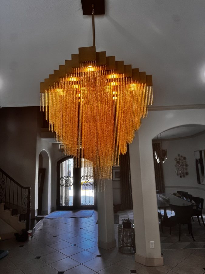 Multi-tier gold crystal chandelier lit in a two-story entry foyer above the staircase